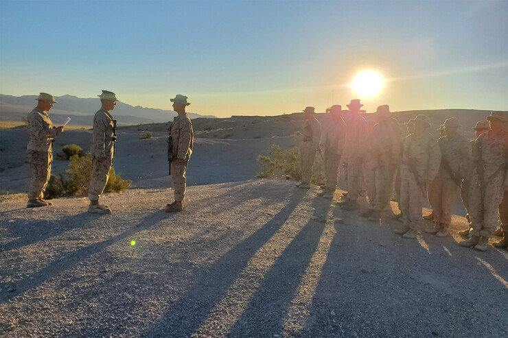 L.J. Bird and fellow Marines stand at attention with a glaring sun behind them