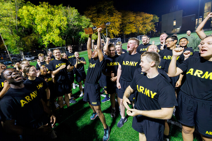 Remy Abdulahi lifts a trophy amid a group of fellow Army ROTC cadets
