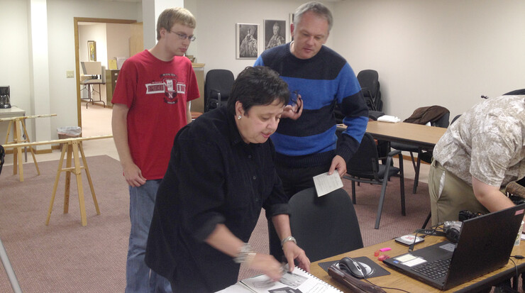 Sherry Loos Pawelko (center) shows some family heirlooms and records to UNL student Matthew Mickelson (left) and Gerald Steinacher, associate professor of history, at the History Harvest Oct. 18 at the American Historical Society of Germans from Russia museum.