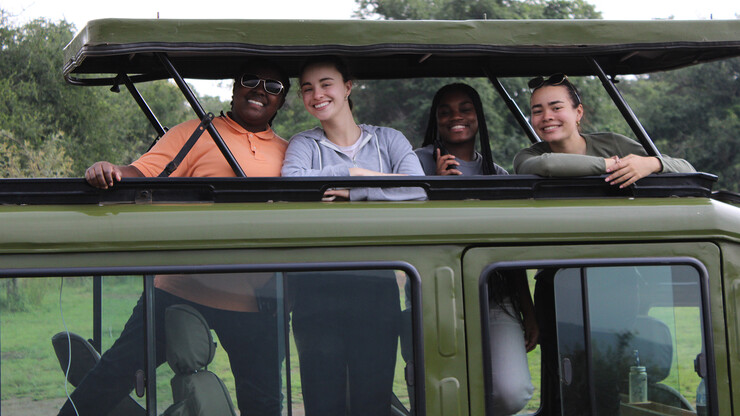 Four students pose in a jeep during the Rwanda trip.