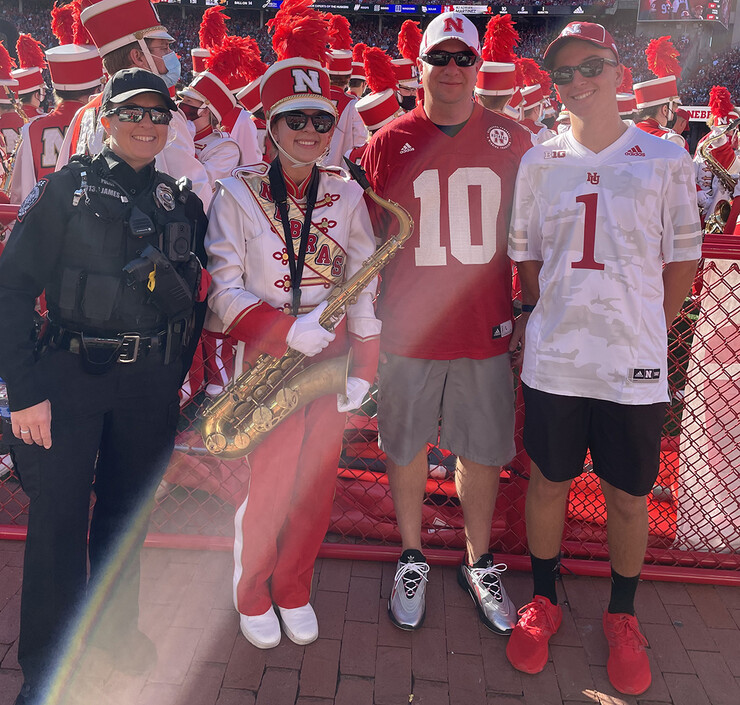 Marissa James poses with her family along the sidelines during a Husker football game. James was a member of the Cornhusker Marching Band, an activity she shares with her daughter.
