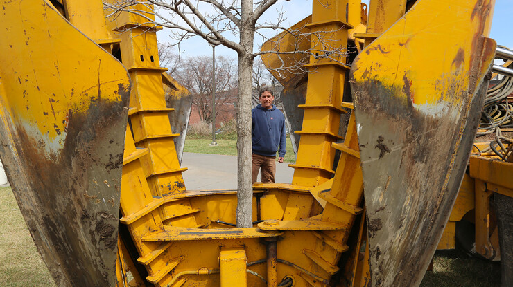 Laurence Ballard inspects the placement of a 90-inch tree spade before a Tablerock sugar maple is removed from the ground east of the new College of Business Administration building construction site on March 26.