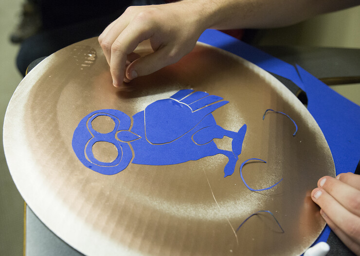 Micah Zetocha glues an owl design on his shield during a Battle of Marathon preparation session Oct. 28 in Andrews Hall.