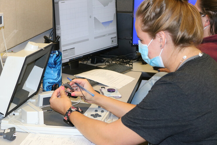 A graduate student prepares a hearing aid device. 
