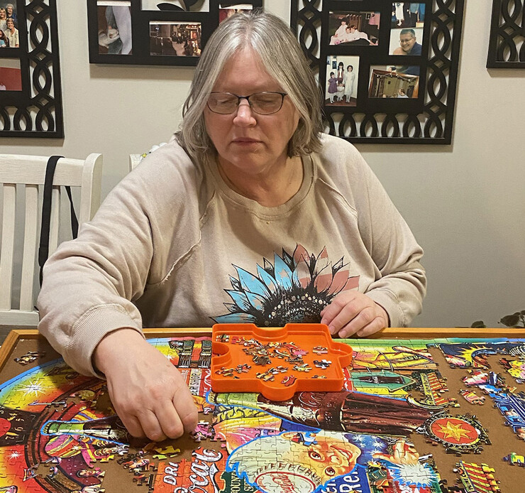 Image of Carol Ruwe sitting at a table putting together a Coca-Cola puzzle.