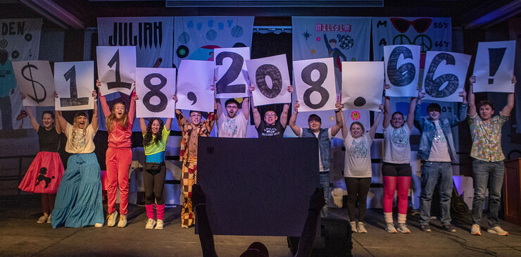 Children supported through Dance Marathon hold up signs revealing the total dollars raised for the 2023 fundraiser.