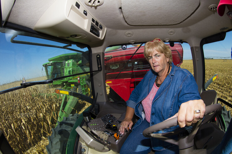 Sharon Portenier drives the tractor pulling the grain wagon. The Portenier farm is located near Harvard, Nebraska.