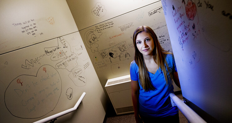 Kate Theimer stands amid abuse victim messages in the stairwell of Lincoln's Child Advocacy Center. Theimer, a Nebraska graduate student, completed a research that found abused teens are more likely to be blamed if the abuse occurred more than once.