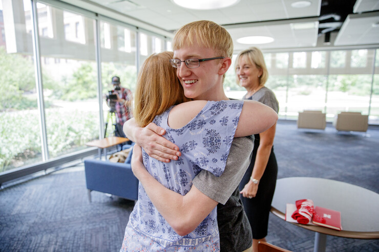 Samuel Harvey is hugged by his mother, Elisia Flaherty, after being presented a scholarship by Donde Plowman