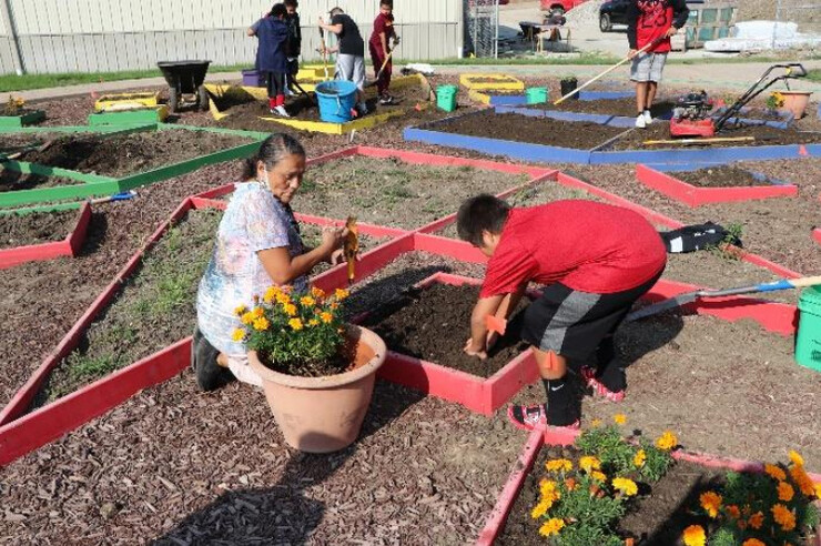 Elder and teacher Delberta Frazier sows traditional plants with students in the Umonhon Nation Public School garden.