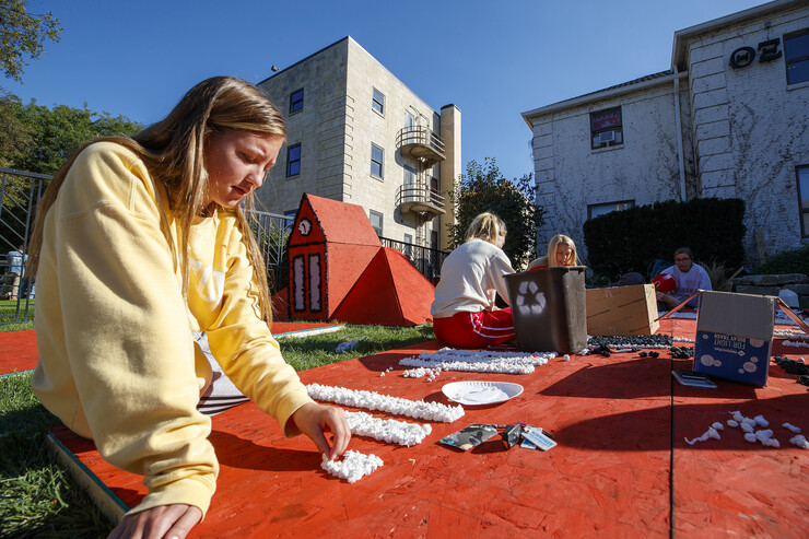 Anna Heinrich, then a freshman, glues poms to a plywood display outside the Theta Xi house in October 2019. Students from Theta Xi, Alpha Phi, Kappa Alpha Theta and Phi Kappa Theta collaborated on the homecoming display.