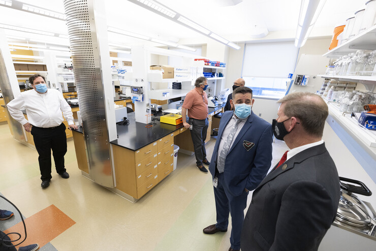 Joshua Santarpia (second from right), NSRI research director, answers a question from NU President Ted Carter (right) during a tour of the new Collaborative Biosecurity Laboratory on Sept. 27.