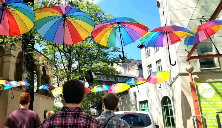 Group of young men walking down street with colorful umbrellas hanging overhead