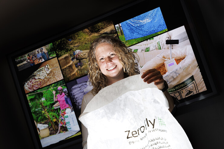 Georgina Bingham holds a ZeroFly bag in a dark room with photos in the background.