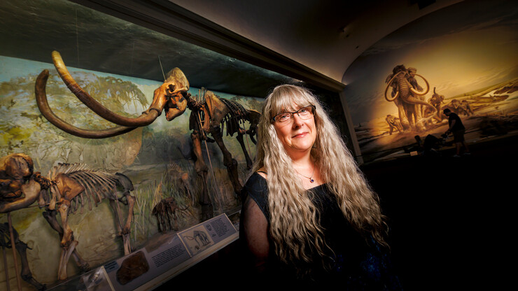 Kate Lyons stands in front of woolly mammoth skeletons at Morrill Hall