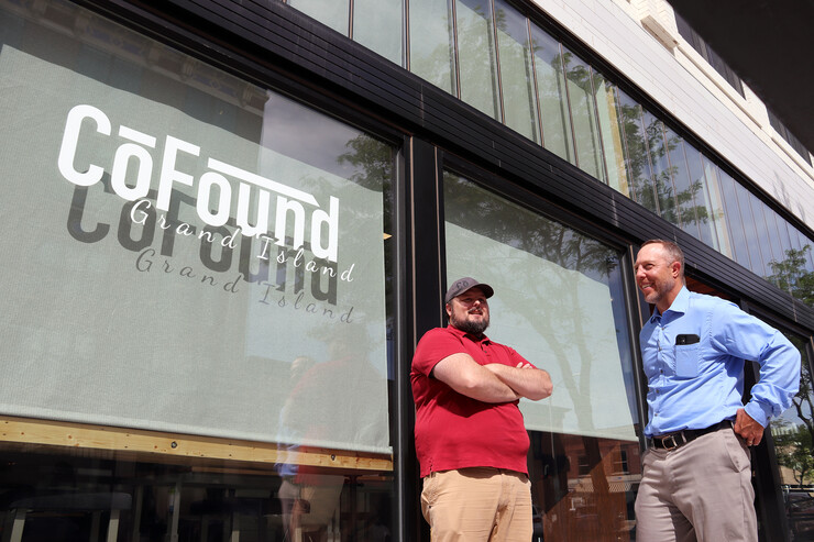 Shawn Kaskie (right) talks with Jonathan Rhoades in front of a glass storefront with the CoFound logo. CoFound is a collaborative workspace for tech entrepreneurs.