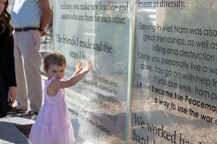 A young girl touches one of the glass panels of the new Veterans’ Tribute.