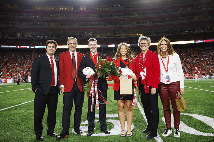 Newly crowned homecoming royalty Jacob Drake (third from left) and Emily Hatterman (fourth from left) are joined by 2021 royalty Bobby Martin (left), Chancellor Ronnie Green (second from left), Jane Green (fifth from left) and Nebraska Alumni Association Executive Director Shelley Zaborowski (right).
