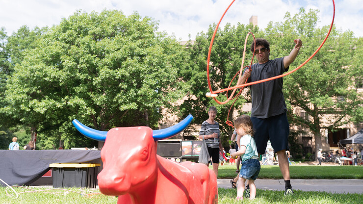 A man prepares to throw a lasso at a red plastic bull.