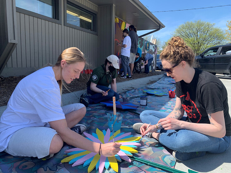 Peace Corps Prep students Kenzie Steiner and Katie Schmitz paint a mural during a group volunteer opportunity at the LUX Center for the Arts in May 2022.