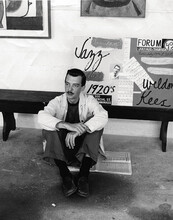 A black-and-white photo of artist Weldon Kees sitting on the ground.