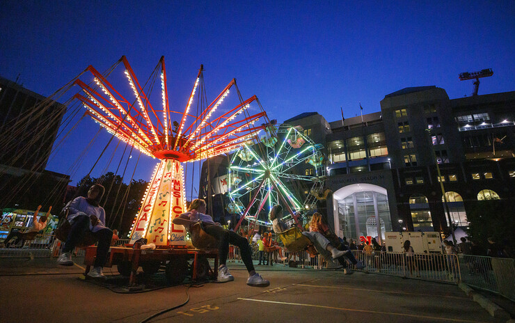 The Musical Chairs ride and Ferris wheel light up the East Stadium Plaza during the 2022 Cornstock Festival.