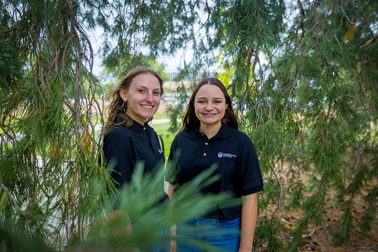 Husker undergraduates Abigail Schroeder (left) and Emma Kurtz are seen amid a tree's dangling branches.