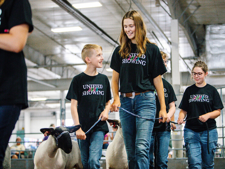 Josh Layman, showman, leads his lamb as a member of the Unified Showing 4-H Club, accompanied by buddy Tatum Terwilliger.