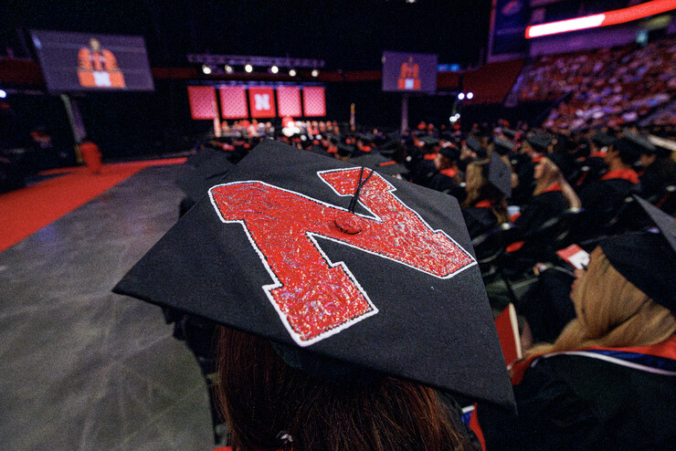 A graduate wears a mortarboard with a large Husker N on top during August commencement at Pinnacle Bank Arena.