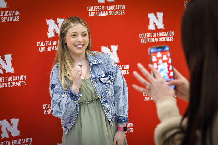 Second-year student Taylor Kirlin holds up a commemorative pin as she poses for a smartphone photograph.