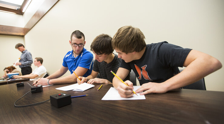 Tucker Merz, Justin Ernst and Preston Deckinger of Falls City High School ponder a math question posed by UNL's Mark Walker as they take on a team from Seward High School. 