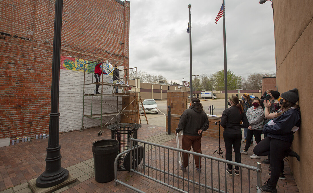 Students watch as a stencil design is finalized in the Havelock Avenue mural.