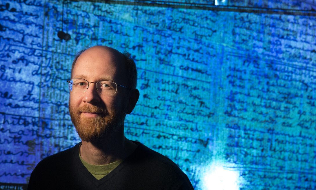 drian S. Wisnicki, assistant professor of English,  stands in front of a projected image of Dr. David Livingstone's  1871 diaries made readable using spectral imaging technology.