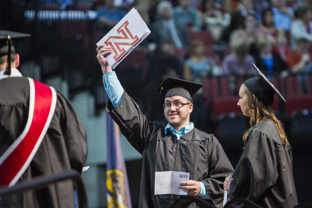 Kyle Sass holds up his two diplomas.