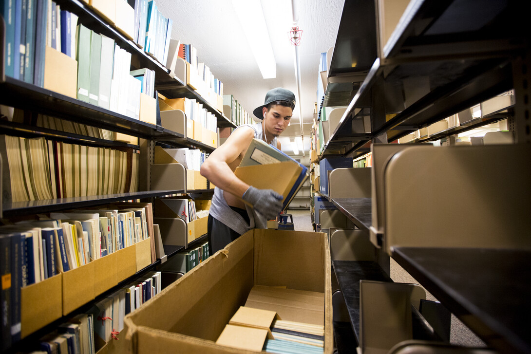 Jonny Reico with VonRentzell Movers packs books in the third floor stacks of Love Library South as part of the Learning Commons Project. Work on the project started in July.