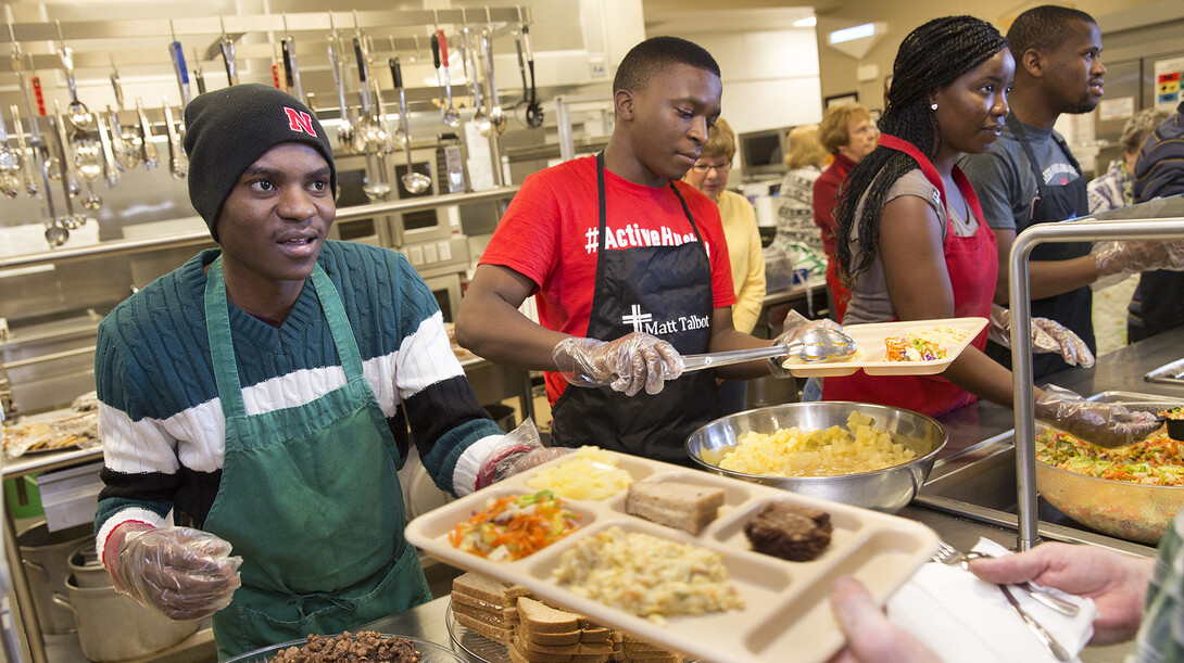 SUSI students (from left) lbinasio (Angola), Mzingaye (Zimbabwe), Kama (Angola) and Mompati (Botswana) help serve lunch at the Matt Talbot Kitchen on Jan. 27.