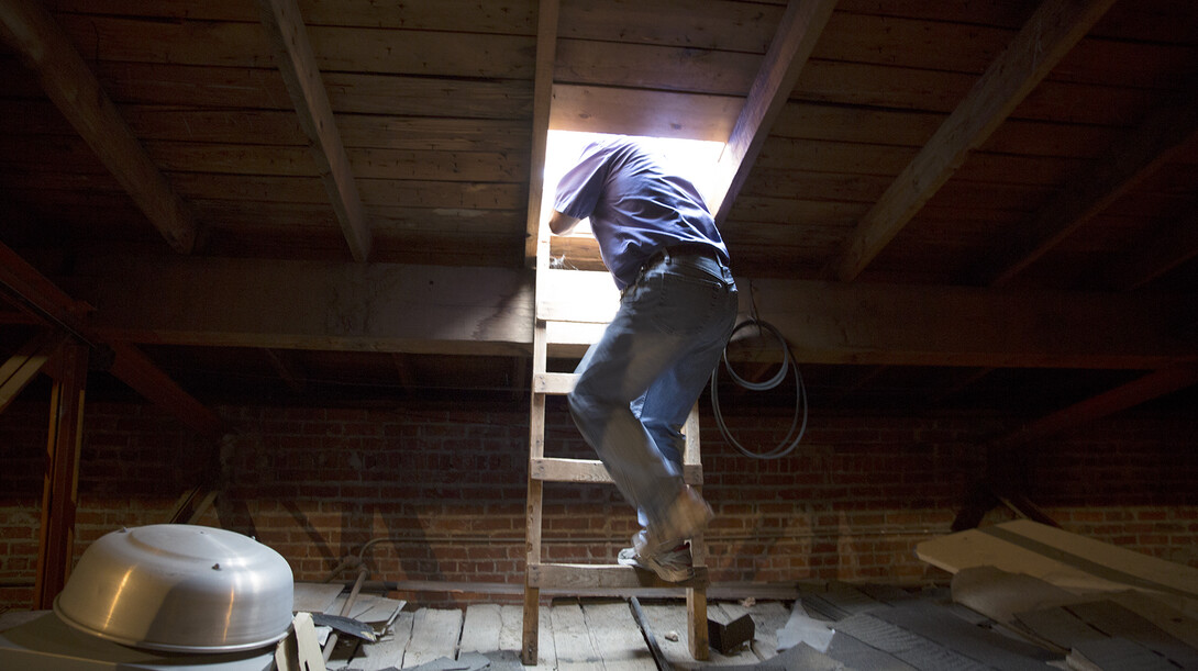 Bryan Ludemann climb through a hatch to assess possible leaks on the roof of Chase Hall on June 11.