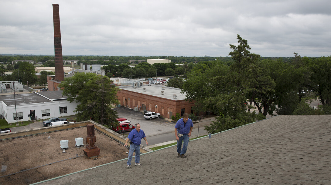 UNL's Bryan Ludemann (left) and Scott Hunt look for possible trouble spots on the roof of Chase Hall on June 11.