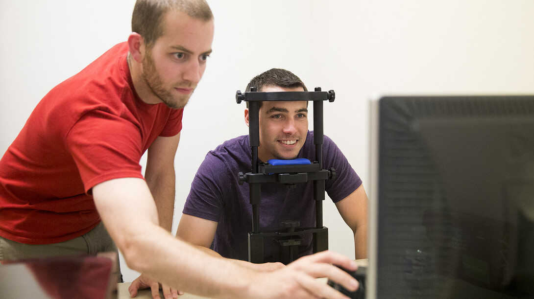 Mark Mills (left), professor of political science, sets up an eye track computer as part of a study.