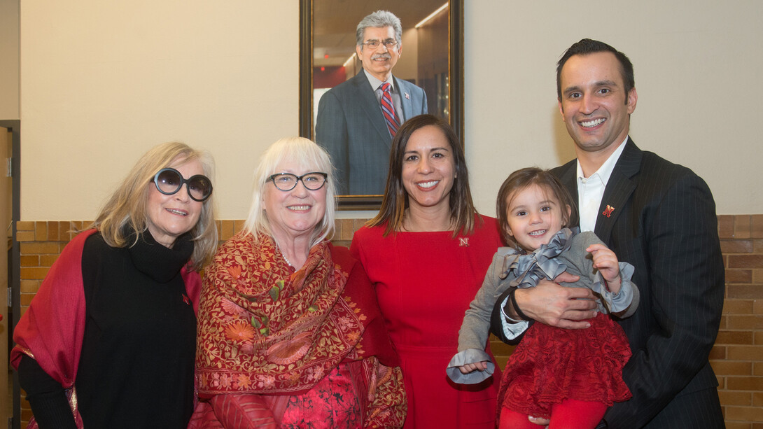 Prem S. Paul’s family stands in front of a portrait of Nebraska’s longtime vice chancellor for research and economic development. Pictured (from left) is Kiki Fink, Missi Paul, Neena Paul and Ryan Paul, who is holding granddaughter Ashland. Fink is Missi Paul’s sister.