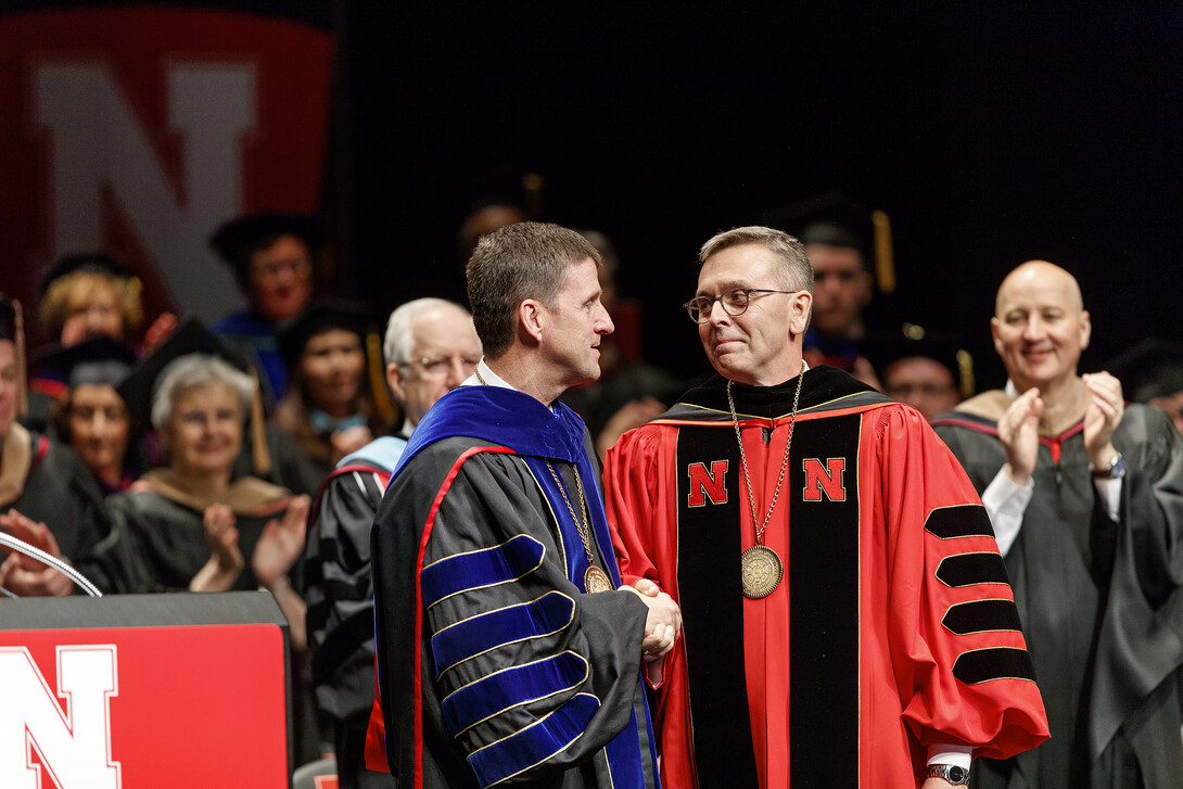 Hank Bounds (left), president of the University of Nebraska system, congratulates Chancellor Ronnie Green after officially installing Green as Nebraska's 20th chancellor. Gov. Pete Ricketts applauds in the background.