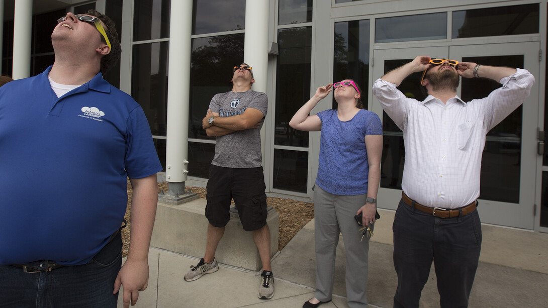 NIMBUS Lab members (from left) Andrew Rasmussen, Adam Plowcha and Brittany Duncan, and Jarrett Ramsay, a Nebraska alumnus, view the eclipse outside the Schorr Center.