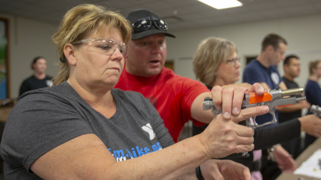 Sergeant Bryan Warner (in red) shows Beth Cullinane how to release the safety on a Smith and Wesson 9mm pistol during the Citizens' Police Academy on Sept. 26. The pistols were once used by university police, but have been converted to use training rounds.