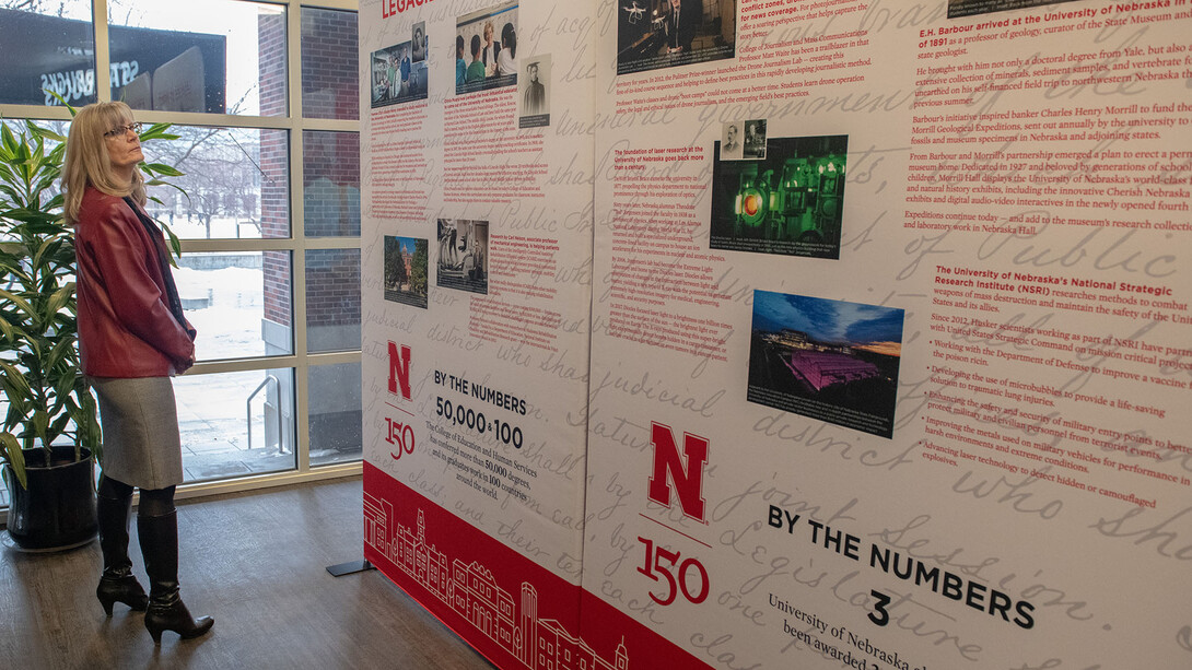 Nebraska's Diane Mendenhall reads about a key historic moment in the university's history as she looks at the N150 traveling exhibition in the Nebraska Union.