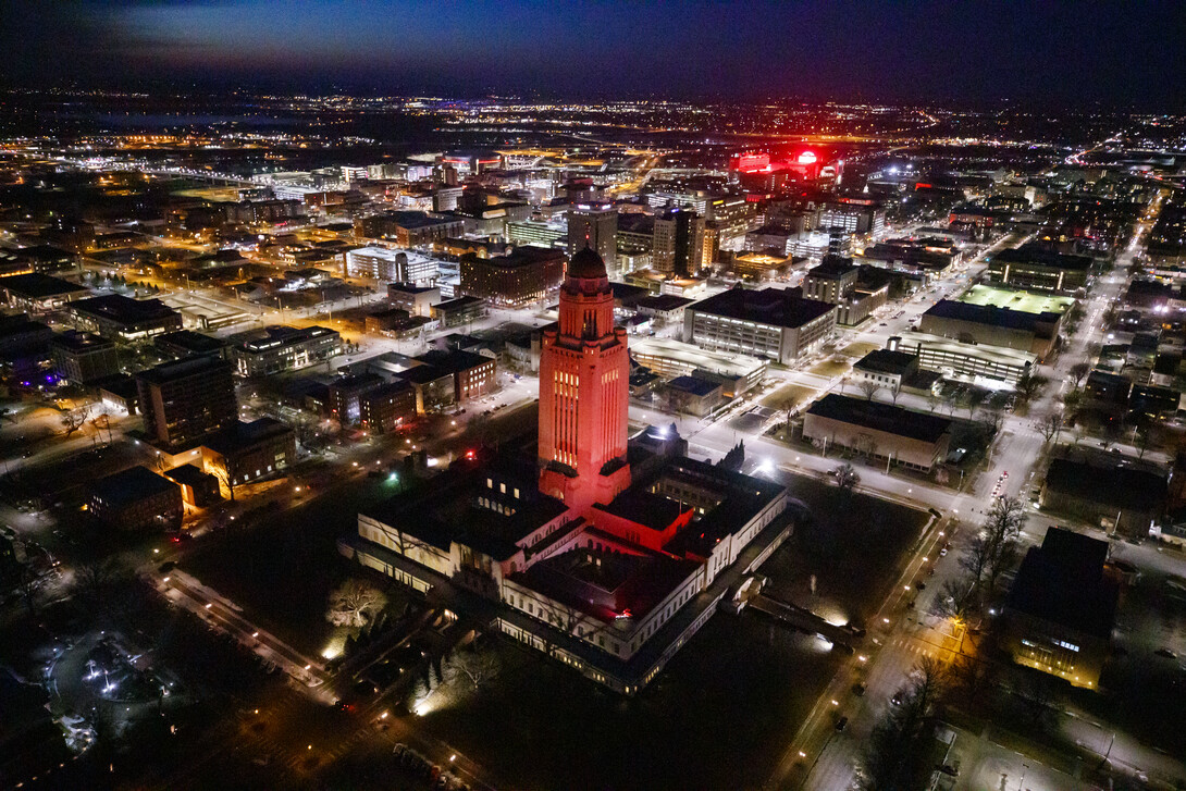 The Nebraska State Capitol shines red with Memorial Stadium and City Campus in the background.