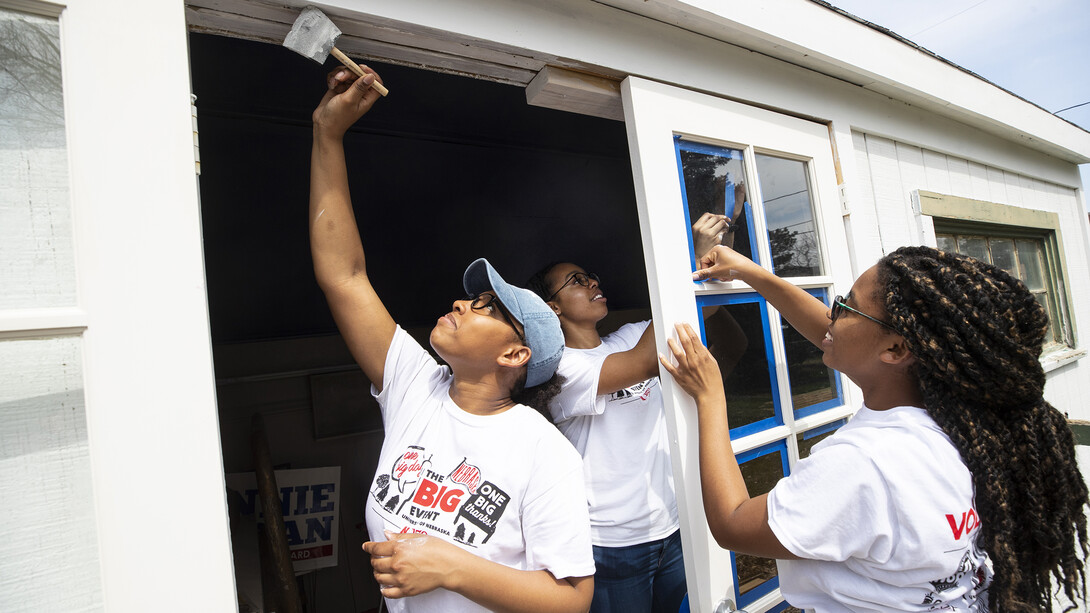 Nebraska's Iesha Bryant reaches for the top of the doorway as she and others in the Minority Pre-Health Association painted a shed and cleaned up a yard during the 2019 Big Event on April 6. More than 2,500 students, faculty and staff volunteered for the community service project.