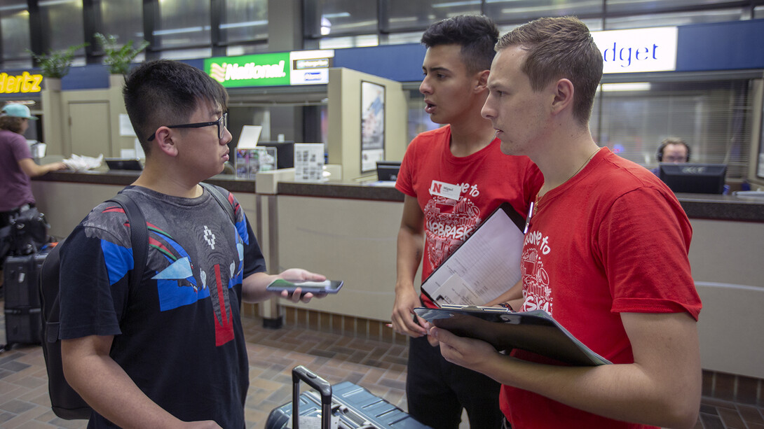 Simon Chen (left) talks with two members of the Nebraska welcome team after his arrival in Lincoln.