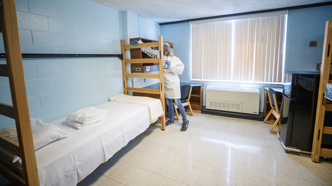 Cheryl Duncan, a residence hall custodial leader with University Housing, wears personal protective equipment as she demonstrate how the residence hall rooms will be cleaned. The face shields and Tyvek gowns Duncan is wearing were manufactured at Nebraska Innovation Campus. 