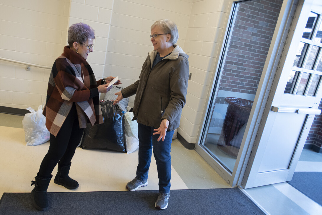 Dee Ebbeka hands Linda Kern, of Clinton Elementary School, the last of the Caring for Clinton donations Dec. 6, 2019, at the school on Holdrege Street.