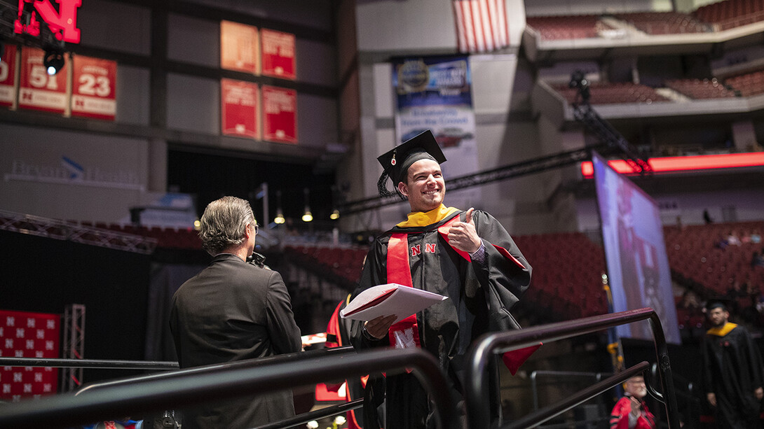 Tyler Moravec of Omaha gives his family and friends a thumbs-up after receiving his Master of Science in construction engineering and management May 3 during the graduate and professional degree ceremony at Pinnacle Bank Arena.